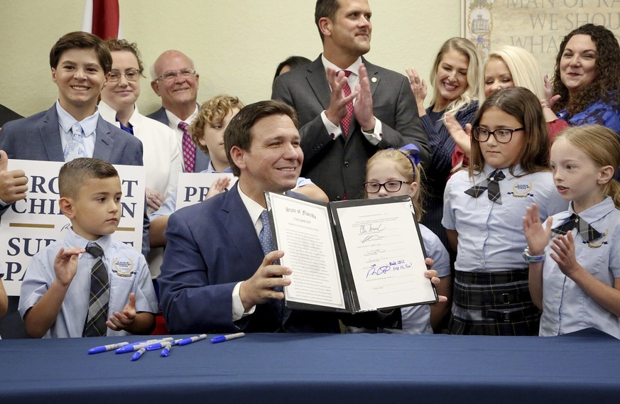 Florida Gov. Ron DeSantis displays the signed Parental Rights in Education, aka the Don&#039;t Say Gay bill, flanked by elementary school students during a news conference on Monday, March 28, 2022, a ...