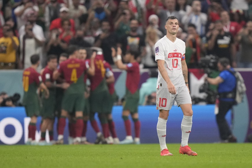 Switzerland's Granit Xhakawalks as Portugal's players celebrate their fourth goal background during the World Cup round of 16 soccer match between Portugal and Switzerland, at the Lusail Stadium in Lu ...