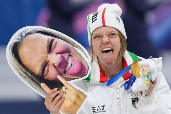 <p>Arianna Fontana hält ein Schild mit dem Gesicht der neuen Olympiasiegerin in der Mixed-Staffel im Shorttrack.</p>