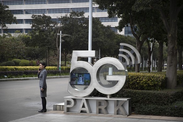 A Huawei employee talks on her cellphone as she stands next to a sign at Huawei&#039;s campus in Shenzhen in southern China&#039;s Guandong Province, Thursday, Dec. 5, 2019. Chinese tech giant Huawei  ...