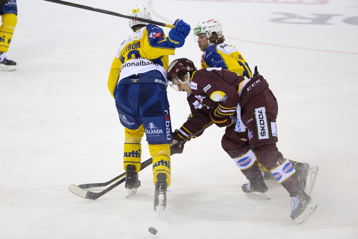 Geneve-Servette's defender Roger Karrer, center, vies for the puck with Davos' players center David Ullstroem, of Sweden, left, and defender Sven Jung, right, during a National League regula ...