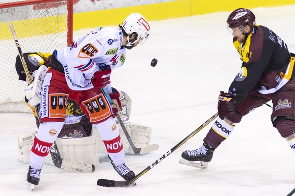 Le joueur St Gallois, Roman Schlagenhauf, centre, a la lutte pour le puck avec le joueur genevois, Jonathan Mercier, droite, devant le gardien genevois, Gauthier Descloux, gauche, lors du match du cha ...