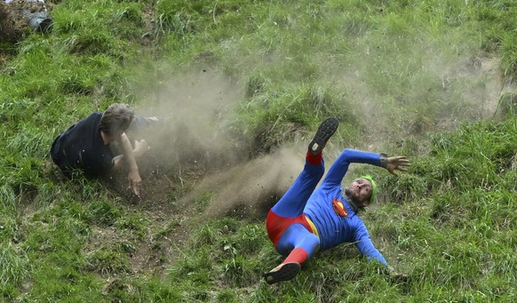 Participants compete in the men&#039;s downhill race category of the traditional annual Cheese Rolling contest at Cooper&#039;s Hill in Brockworth, Gloucestershire, England, Monday, May 26, 2025.(AP P ...