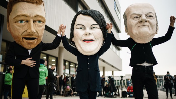 epa09518123 Activists of Campact wearing masks resembling (L-R) Free Democratic Party (FDP) chairman and faction chairman in the German parliament Bundestag Christian Lindner, Green party (Die Gruenen ...