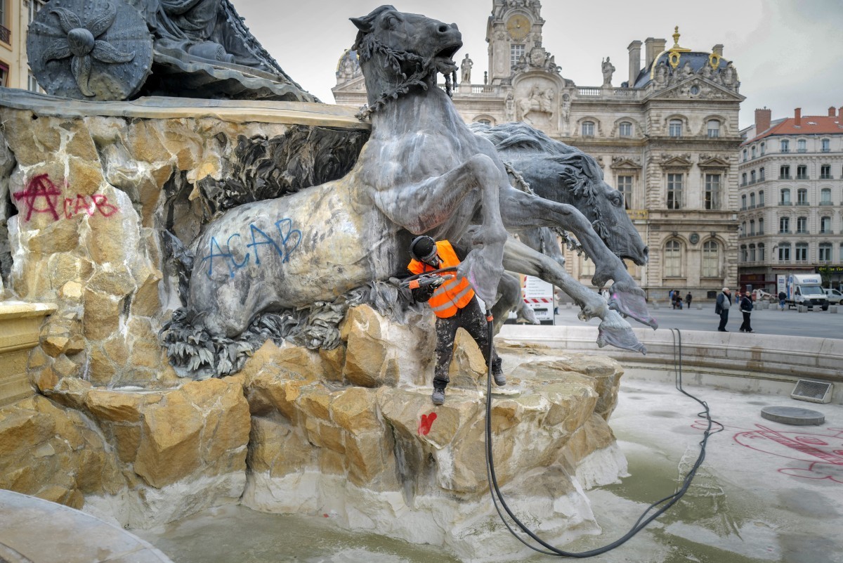 A city hall employee removes graffitis on the Bartholdi Fountain in Place des Terreaux, in Lyon on October 19, 2026 two days after riots and looting occurred on the sidelines of nationwide cost-of-liv ...