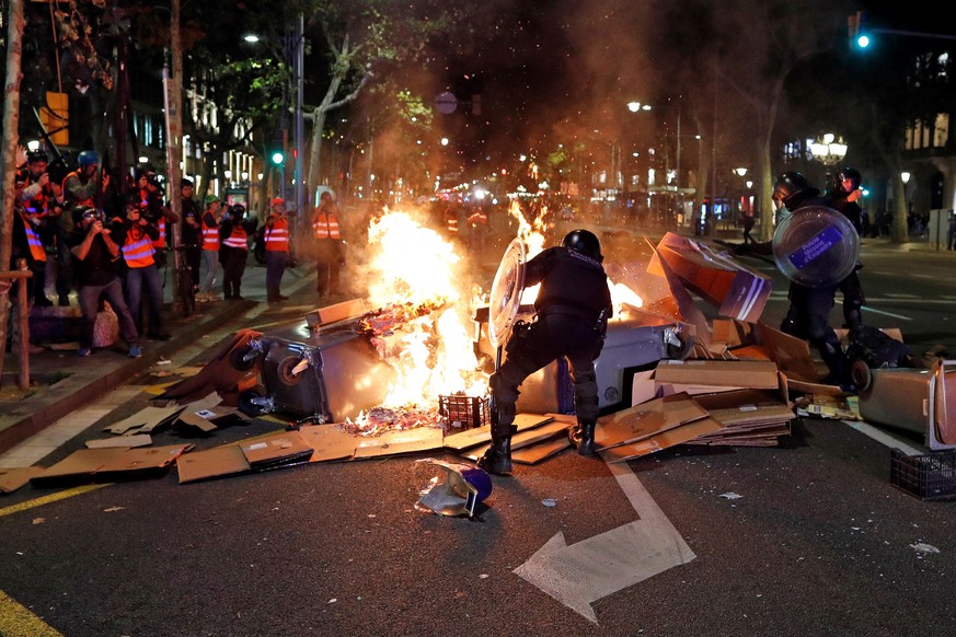 epa07952172 Catalan regional Riot police members try to put out the fire of a barricade during a protest in Barcelona, Spain, 26 October 2019. Catalonia region in Spain is witnessing massive demonstra ...