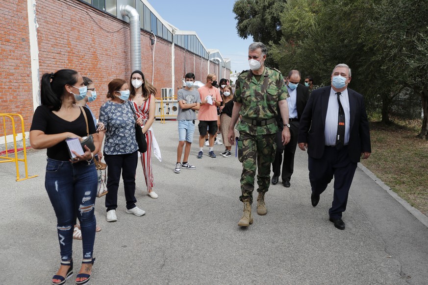 Portugal Vaccine Success - Rear Admiral Henrique Gouveia e Melo, center, talks to people queuing outside a vaccination center in Lisbon, Saturday, Sept. 11, 2021. As Portugal nears its goal of fully v ...