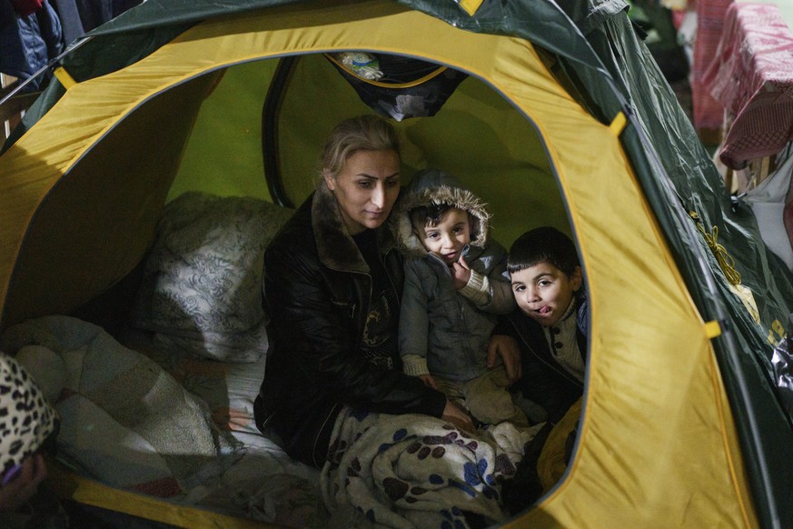 A woman sits with her children inside the tent at the &quot;Bruzgi&quot; checkpoint logistics center at the Belarus-Poland border near Grodno, Belarus, Thursday, Dec. 23, 2021. Since Nov. 8, a large g ...