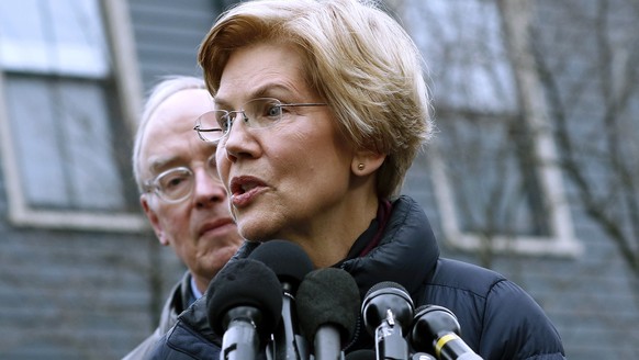 Sen. Elizabeth Warren, D-Mass., speaks beside her husband Bruce Mann, left, outside their home, Monday, Dec. 31, 2018, in Cambridge, Mass., where she confirmed that she is launching an exploratory com ...