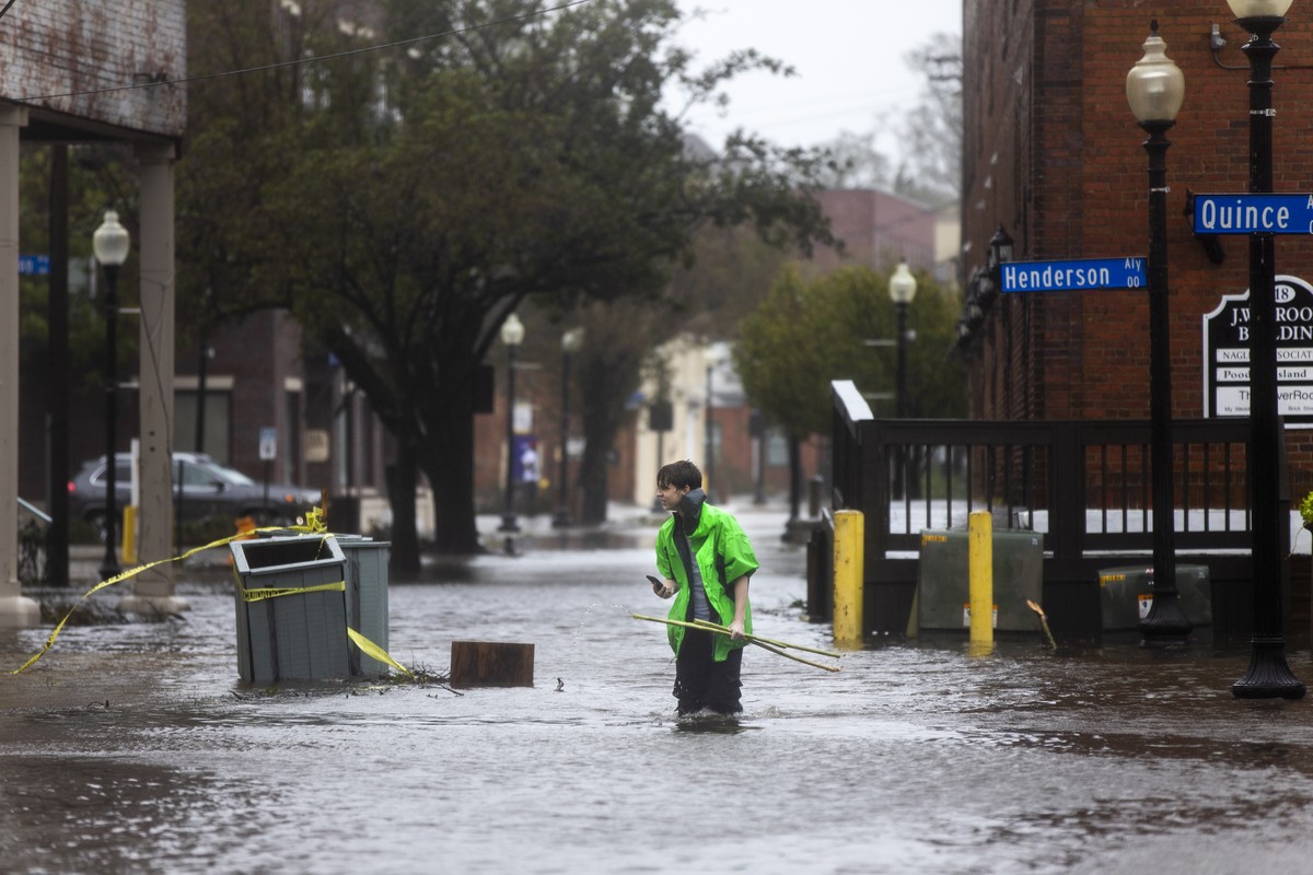 epa07020751 Sam Parks walks through flooded Water Street as Hurricane Florence comes ashore in Wilmington, North Carolina USA, 14 September 2018. Hurricane Florence has been downgraded to a category 1 ...