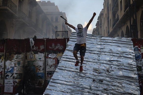 A man jumps from a barrier blocking the access to the parliament building during an anti-government protest, in the aftermath of last Tuesday&#039;s massive explosion which devastated Beirut, Lebanon, ...