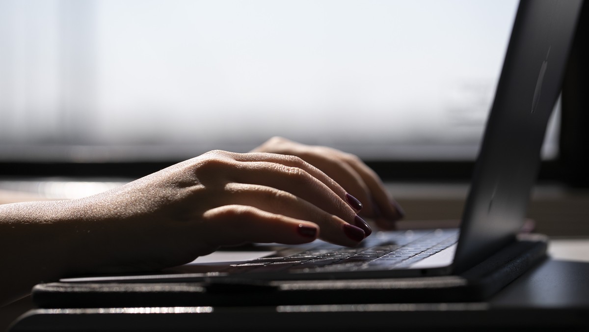 FILE - A woman types on a laptop while on a train in New Jersey, May 18, 2021. A trial of a four-day workweek in Britain, billed as the world's largest, has found that an overwhelming majority of ...