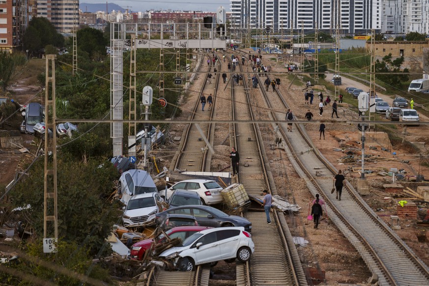 People walk along the train tracks heading toward Valencia in an area affected by floods in Sedavi, Spain, Friday, Nov. 1, 2024. (AP Photo/Manu Fernandez)
