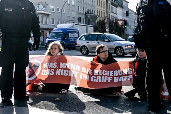 epa10292182 Police intervene as Letzte Generation (Last Generation) climate activists block a road with their hands glued to the asphalt in Berlin, Germany, 07 November 2022. Letzte Generation activis ...