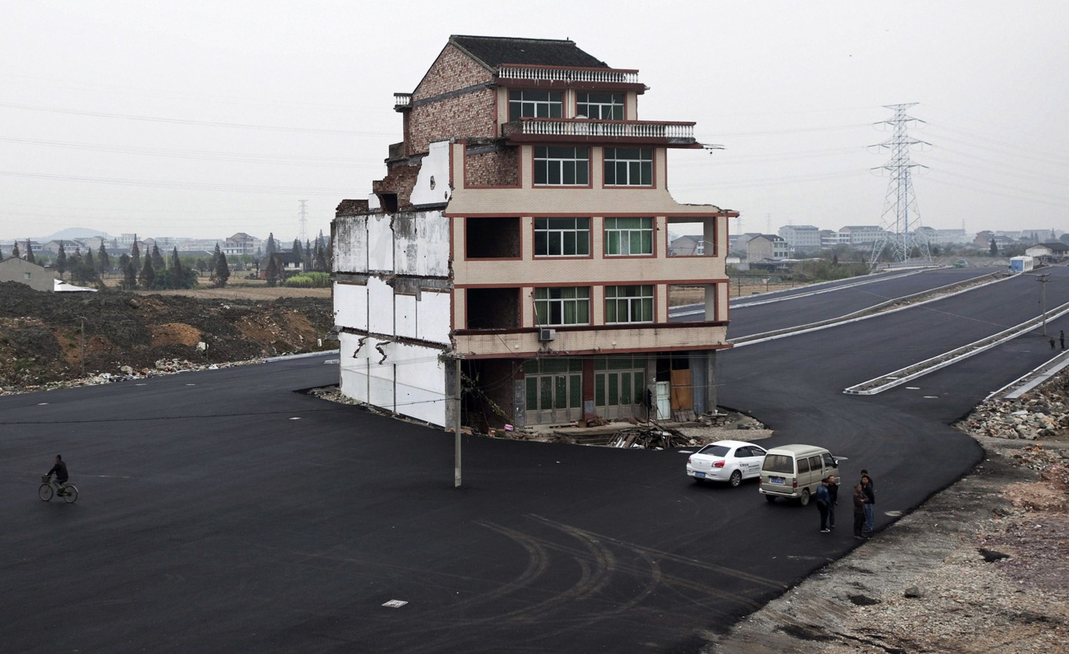 FOR USE AS DESIRED, YEAR END PHOTOS - FILE - FILE - In this Nov. 22, 2012 file photo, people stand near a house sitting in the middle of a new main road on the outskirts of Wenling city in east China& ...