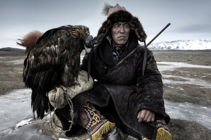 Ein Jäger und sein Jagd-Adler legen in den Weiten der Mongolei eine Pause ein.
