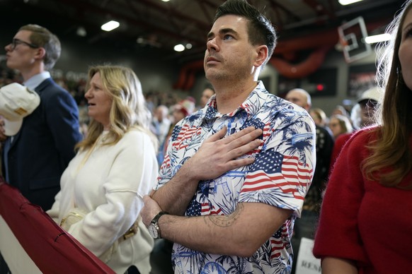 Supporters stand during the national anthem before a former President Donald Trump commit to caucus rally, Saturday, Jan. 6, 2024, in Clinton, Iowa. (AP Photo/Charlie Neibergall)