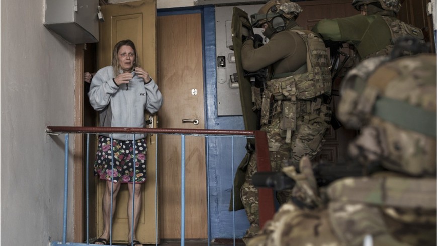 Members of the SBU break into a residential building in search of employees.