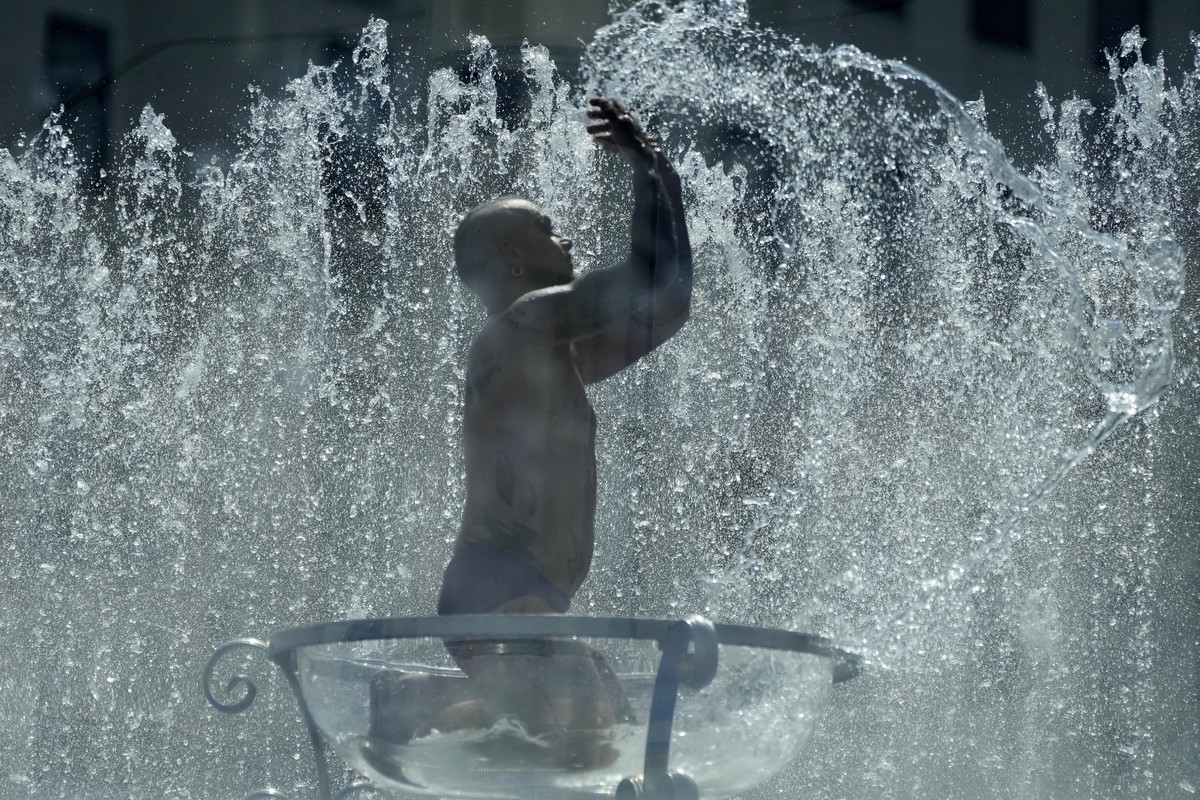 A man sits in a glas bowl in a fountain on the Southbank in London, Tuesday, July 19, 2022. Millions of people in Britain woke from the country's warmest-ever night on Tuesday and braced for a da ...