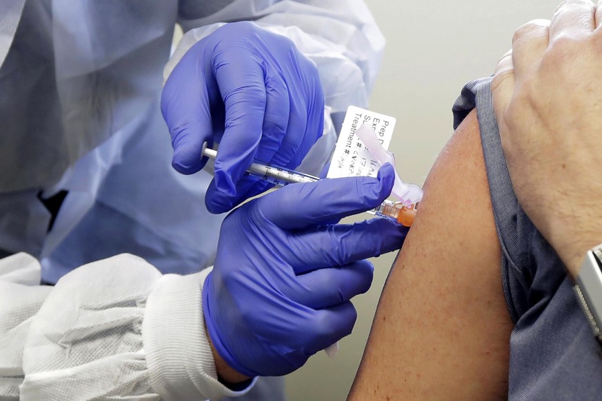 FILE - In this March 16, 2020 file photo, a patient receives a shot in the first-stage safety study clinical trial of a potential vaccine for COVID-19, the disease caused by the new coronavirus, at th ...