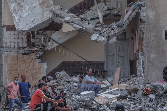 epa09205445 Palestinian civil defense search for people between the rubble of a destroyed houses after an Israeli air strike in Gaza City on, 16 May 2021. Thirteen Palestinian were killed and more tha ...