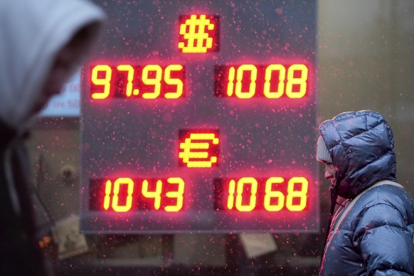 Pedestrians walk in a street near an exchange office sign showing the currency exchange rates of the Russian ruble, U.S. dollar, and euro in Moscow, Russia, Wednesday, Nov. 20, 2024. (AP Photo/Pavel B ...