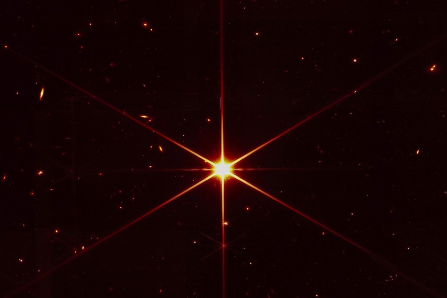 This image made available by NASA on Wednesday, March 16, 2022 shows star 2MASS J17554042+6551277 used to align the mirrors of the James Webb Space Telescope, with galaxies and stars surrounding it. T ...