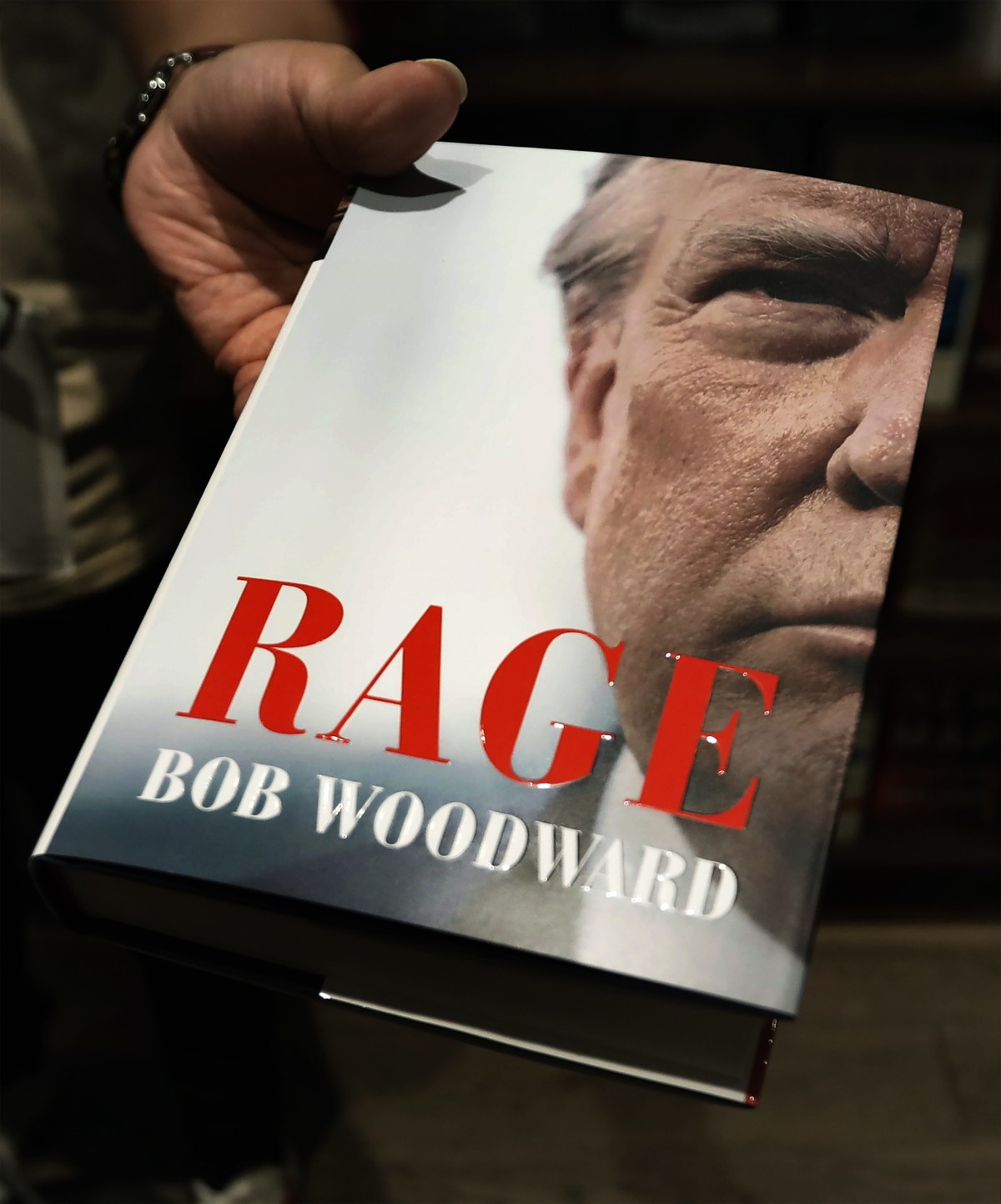 epa08671693 An employee at Shakespeare &amp; Co. holds out the new book by Bob Woodward 'Rage', in New York, New York, USA, 15 September 2020. The book is released after recordings during in ...