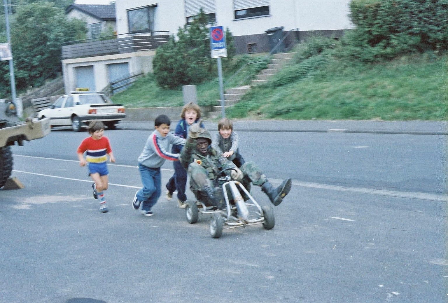 US-Soldat spielt mit einheimischen Kindern auf einem Karren irgendwo in Westdeutschland (1980er Jahr