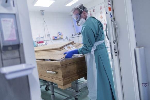 FILE - In this Dec. 18, 2020 file photo, funeral director Christoph Kuckelkorn closes a coffin containing a deceased person who died of or with the coronavirus in Cologne, Germany. Germany announced 2 ...