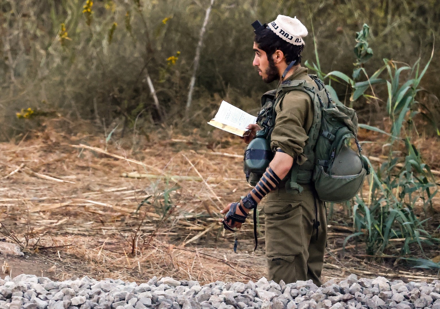 epa10924762 An Israeli soldier prays at a gathering site at an undisclosed location along the Israel-Gaza border, in southern Israel, 18 October 2023. Hundreds of people have been killed by an explosi ...
