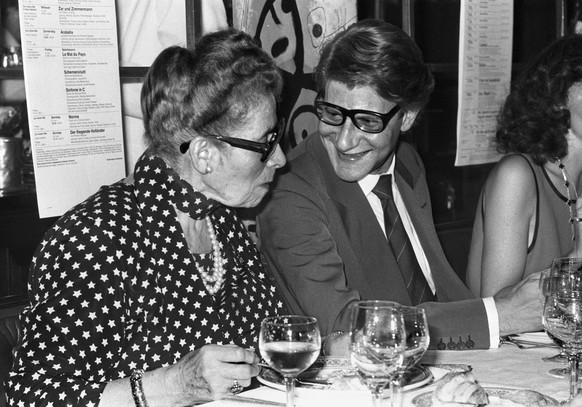 Der Modeschoepfer Yves Saint Laurent, Mitte, und Hulda Zumsteg, links, Wirtin des Restaurants Kronenhalle in Zuerich, erheben waehrend eines Essens in der Kronenhalle am 5. Juni 1979 ihre Glaeser. (KE ...