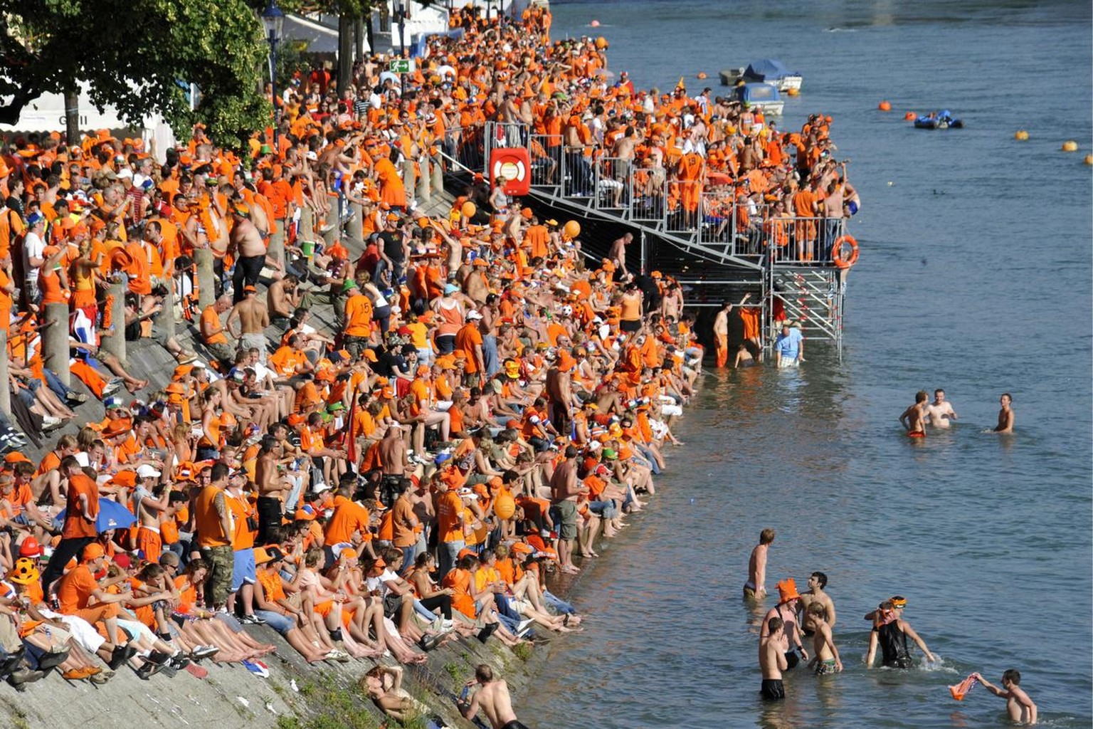 Dutch soccer fans sit on the bank of the Rhine river in Basel, Switzerland, prior to the Uefa Euro 2008 European Soccer Championship quarter final match between the Netherlands and Russia on Saturday, ...