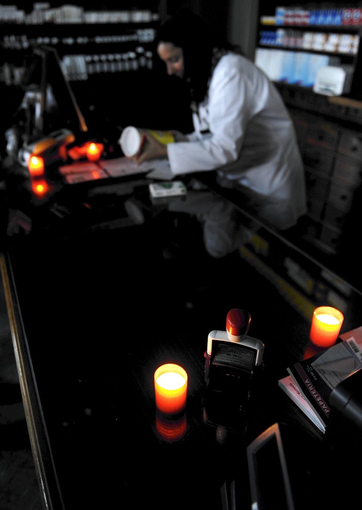 Verkaufen bei Kerzenlicht in der Apotheke beim Zuercher Bellevue nach dem Stromausfall in Zuerich am Donnerstag, 26. Januar 2012. (KEYSTONE/Walter Bieri)