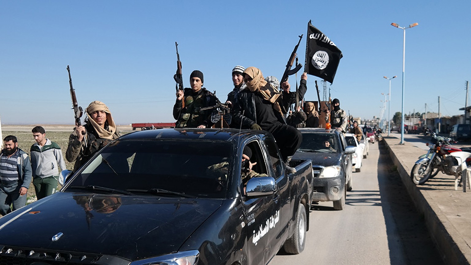 FILE - In this this file photo released on May 4, 2015, on a militant website, which has been verified and is consistent with other AP reporting, Islamic State militants pass by a convoy in Tel Abyad, ...