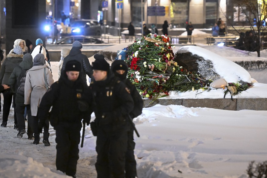 Police guard an area as people lay flowers paying the last respect to Alexei Navalny at the monument, a large boulder from the Solovetsky islands, where the first camp of the Gulag political prison sy ...
