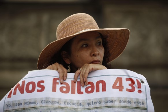 FILE - A woman carries a banner that reads in Spanish &quot;We are missing 43,&quot; referring to the 43 missing students from a rural teachers college during a march in Mexico City, Thursday, Nov. 26 ...