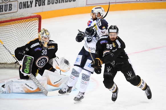 LuganoÕs goalkeeper Elvis Merzlikins, Ambri&#039;s player Elias Bianchi and LuganoÕs player Thomas Wellinger, from left, fight for the puck, during the preliminary round game of National League Swiss  ...