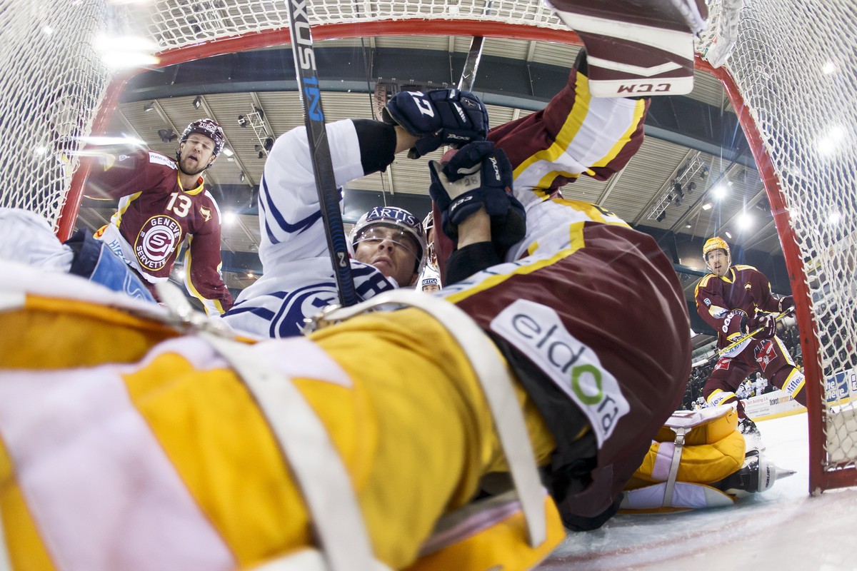 Ambri-Piotta's defender Eliot Berthon, 2nd left, clashes against Geneve-Servette's goaltender Robert Mayer, past Geneve-Servette's forward Nick Spaling, of Canada, left, and Geneve-Serv ...