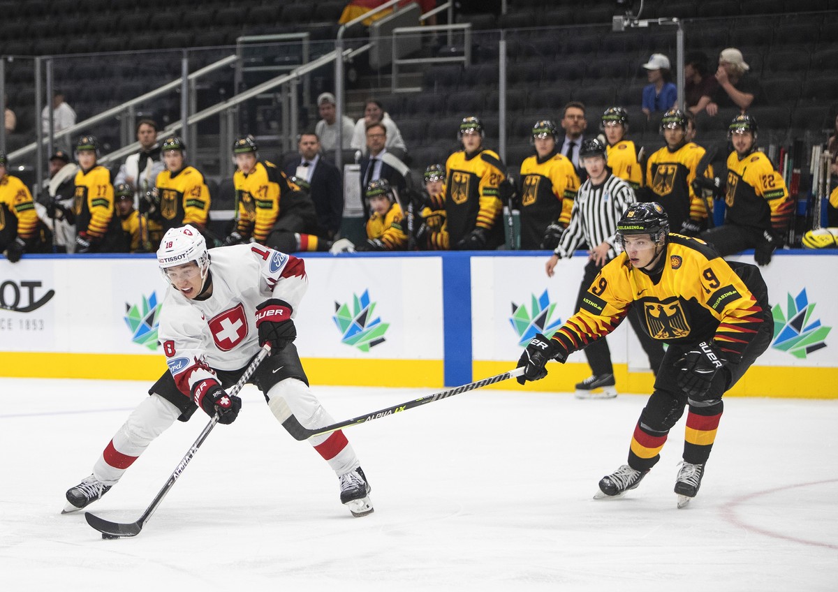 Germany's Haakon Hanelt (19) chases Switzerland's Joshua Fahrni (18) during the first period of an IIHF world junior hockey championships game in Edmonton, Alberta, Saturday, Aug. 13, 2022.  ...