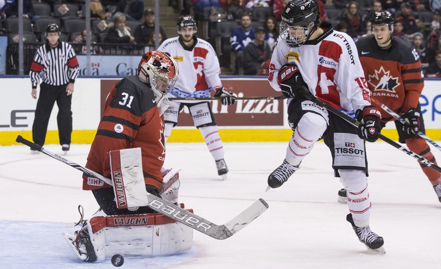 Canada goaltender Carter Hart makes a save in front of Switzerland&#039;s Nico Hischier during the second period of an exhibition game ahead of the IIHF World Junior hockey championships, in Toronto o ...