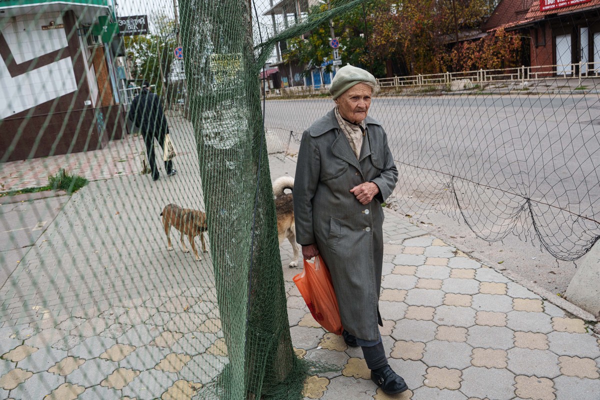 An elderly woman walks beneath anti-drone nets stretched over a street during a local ceasefire related to evacuation efforts in Oleshky, in Kherson, Ukraine, Tuesday, Oct. 27, 2026. (AP Photo/Evgeniy ...