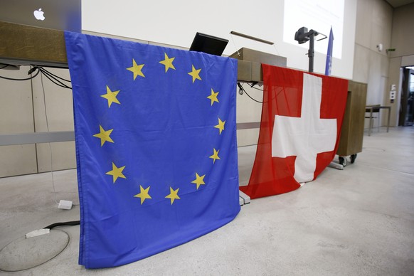 Die Schweizer Flagge und die EU-Flagge haengen ueber einem Tisch waehrend der Generalversammlung der NEBS (Neue Europaeische Bewegung Schweiz) am Samstag, 10. Mai 2014 in Bern. (KEYSTONE/Peter Klaunze ...