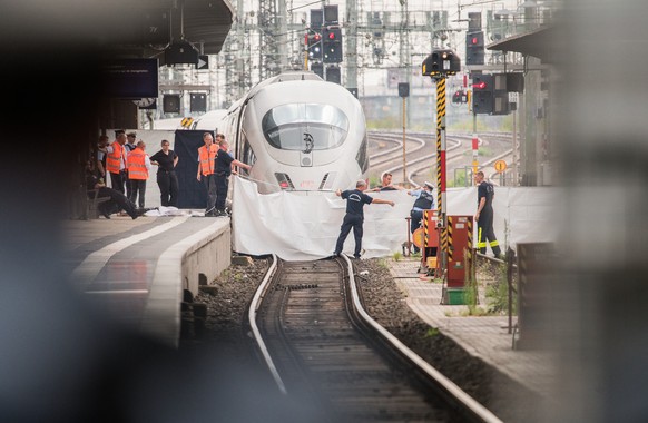 29.07.2019, Hessen, Frankfurt/Main: Polizisten und Feuerwehrleute spannen im Hauptbahnhof eine weisse Plane als Sichtschutz vor einen ICE. Ein achtjaehriger Junge ist im Frankfurter Hauptbahnhof von e ...