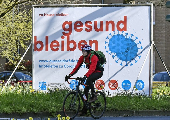 A man cycles by an advertisement reading &quot;stay home, stay healthy&quot; in Duesseldorf, Germany, Monday, March 23, 2020. In order to slow down the spread of the coronavirus, the German government ...