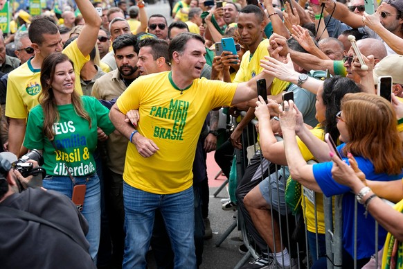Opposition presidential candidate Flavio Bolsonaro and his wife, Fernanda Bolsonaro, greet supporters as they arrive for a presidential election campaign rally in Rio de Janeiro, Brazil, Sunday, Aug.  ...