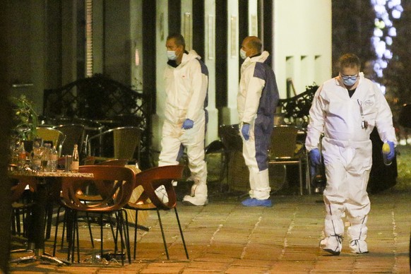 Three persons investigate at the scene following gunfire on people enjoying a last evening out before lockdown in the Austrian capital Vienna, early Tuesday, Nov. 3, 2020. Police in the Austrian capit ...