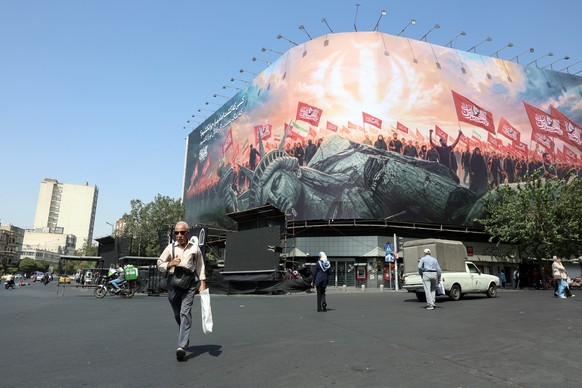 epa13147972 Iranians walk past an anti-US billboard at Enghelab Square in central Tehran, Iran, 03 August 2026. Tensions between Iran and the US over the Strait of Hormuz continue, as US President Don ...