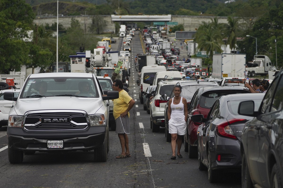 Des personnes attendent à l'extérieur de leur voiture que les équipes de réparation dégagent les routes après le passage de l'ouragan Otis.