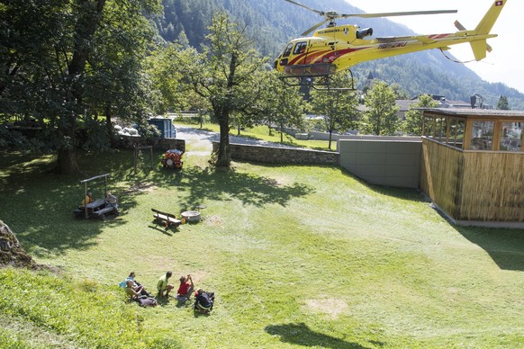 epa06160013 A group of hikers ducks after beeing evacuated from a cut-off mountain hut by a helicopter in Bondo, Graubuenden in southern Switzerland, 24 August 2017. The village had been hit by a mass ...